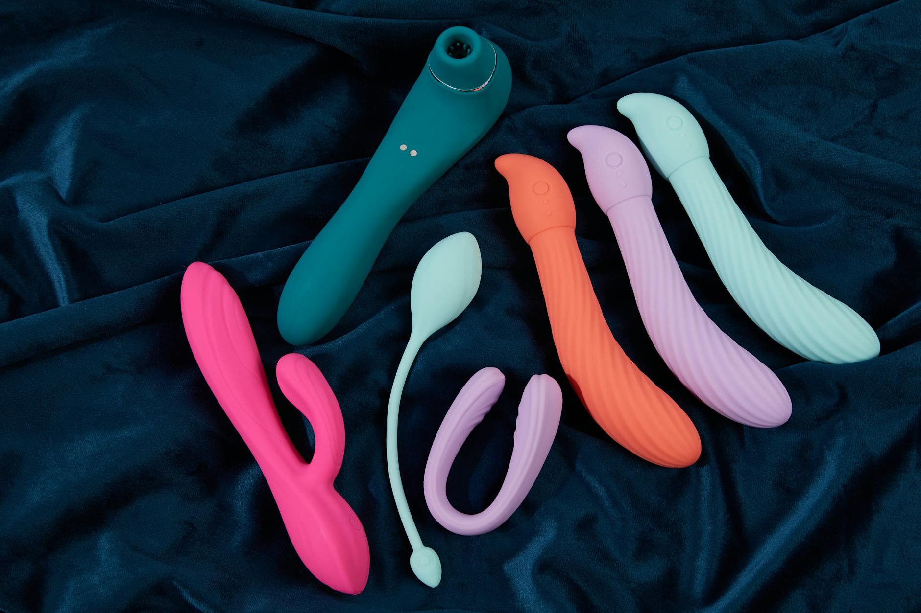Various silicone vibrators displayed on dark blue fabric