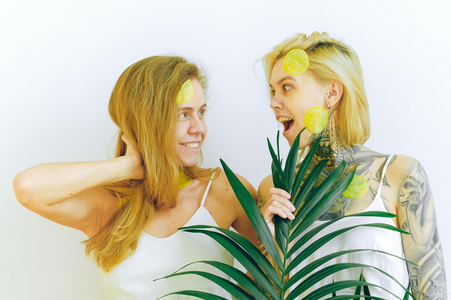 Two women laughing together with joy while holding citrus, expressing confidence and celebration