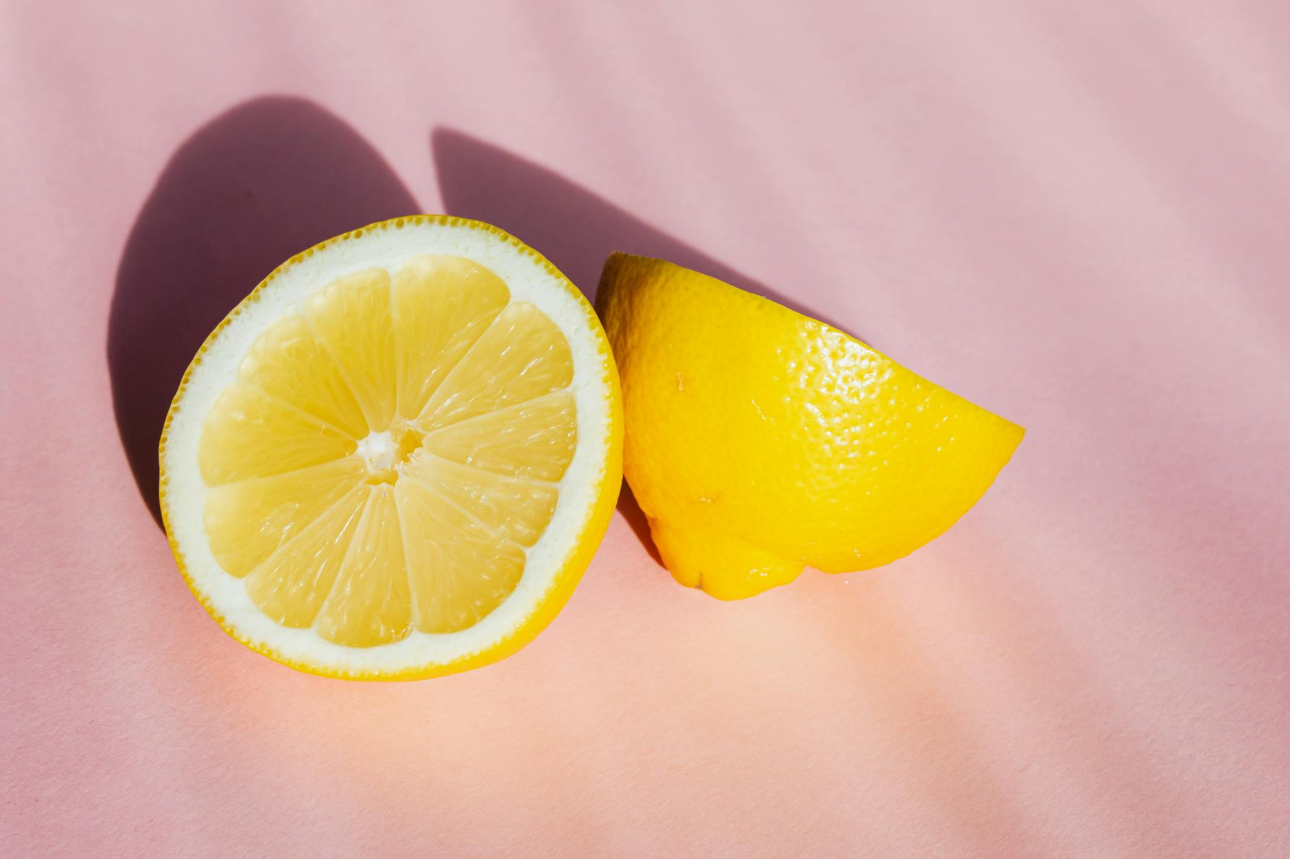 Bright fresh lemons on a soft pink background, symbolizing the natural shifts that come with hormonal changes