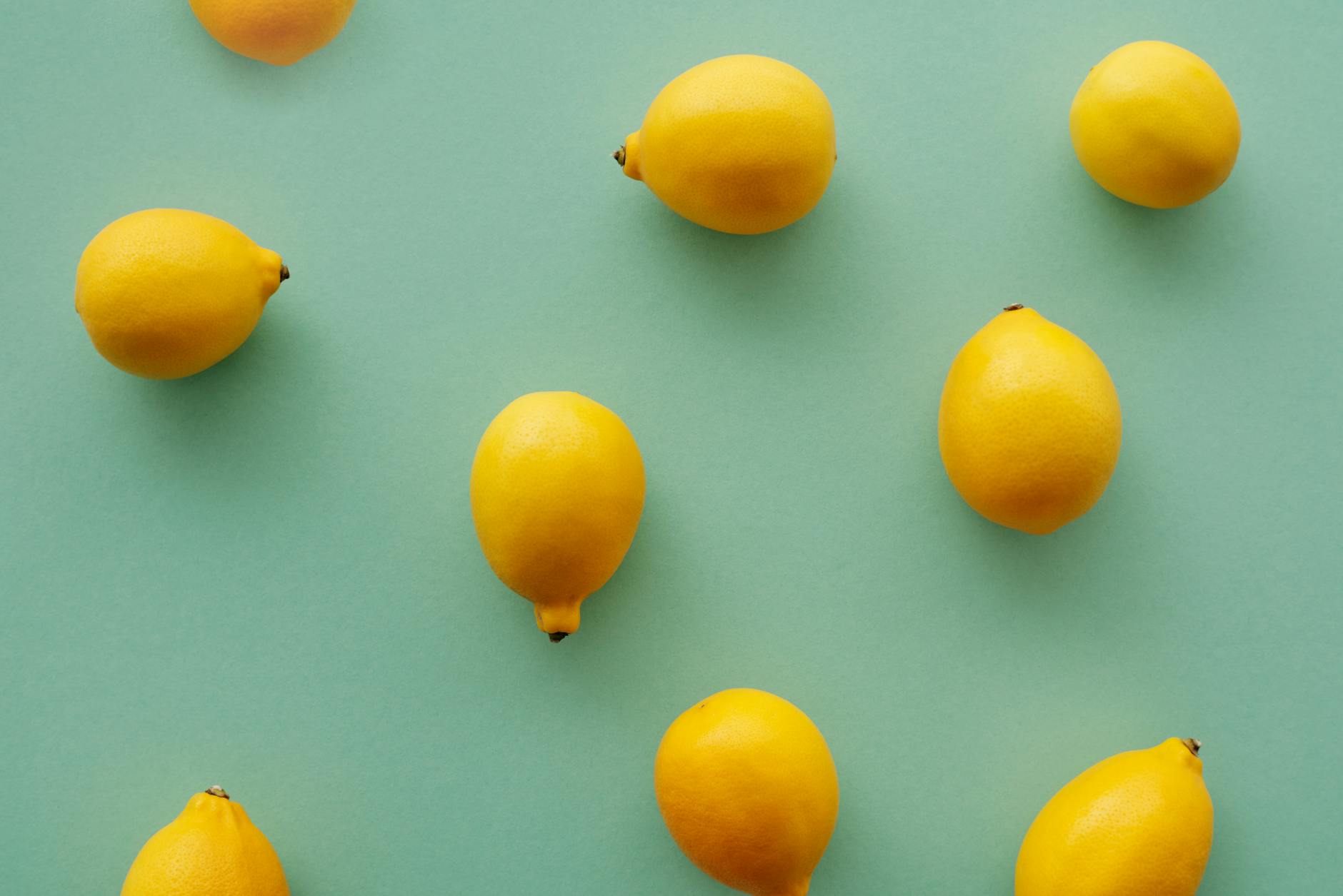 Hand holding a fresh lemon against a vibrant yellow background, conveying citrus freshness and vitality