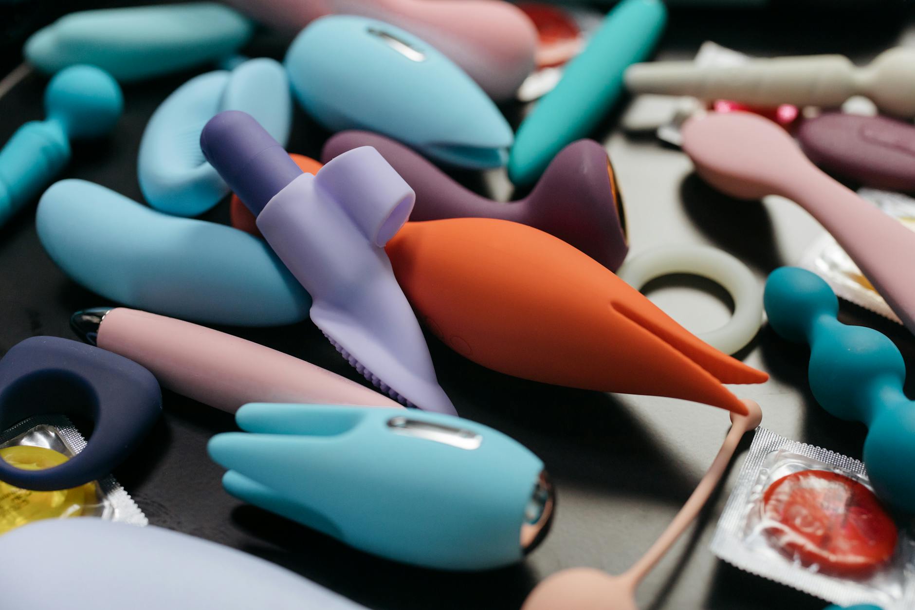 A blue silicone clitoral vibrator held in hand against a solid purple background