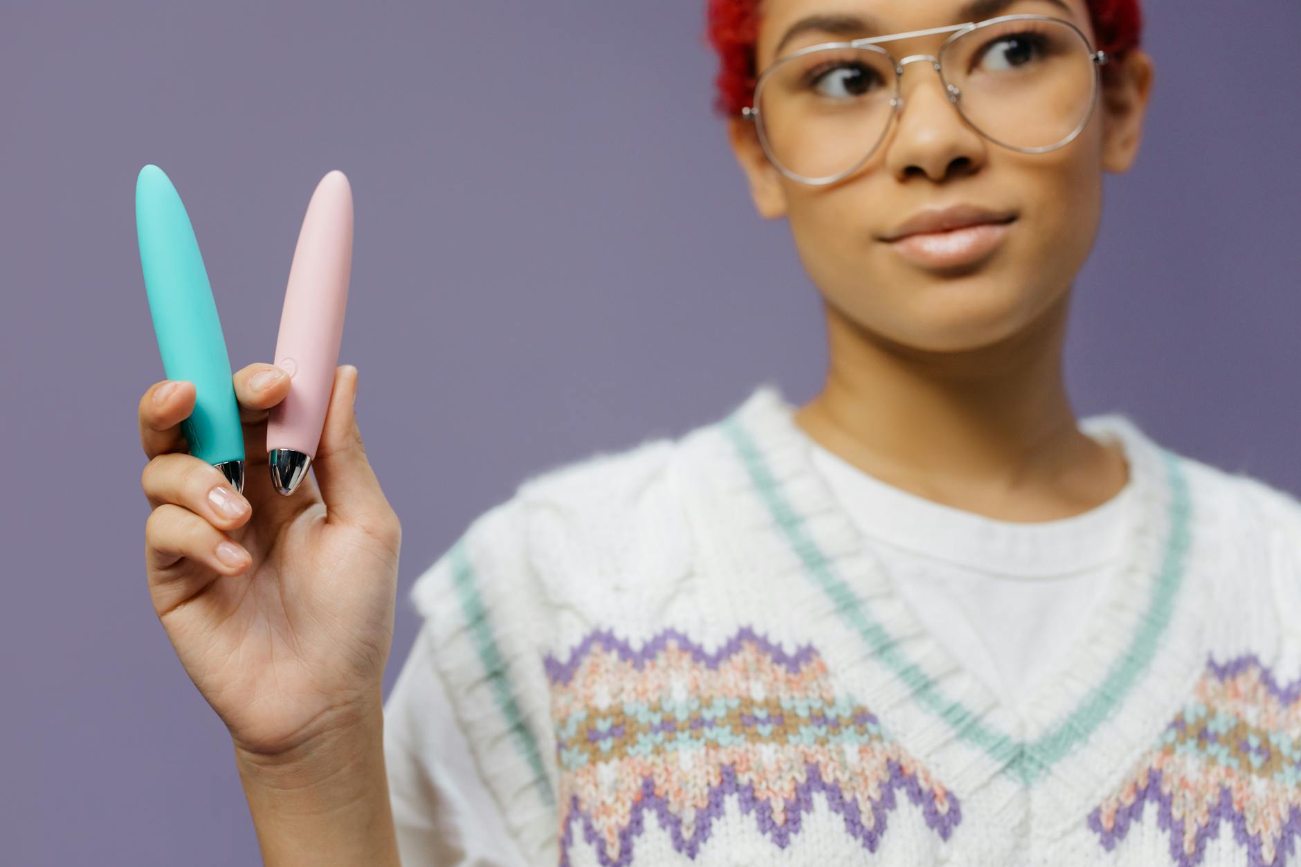 Mãos segurando um vibrador azul elegante em fundo roxo