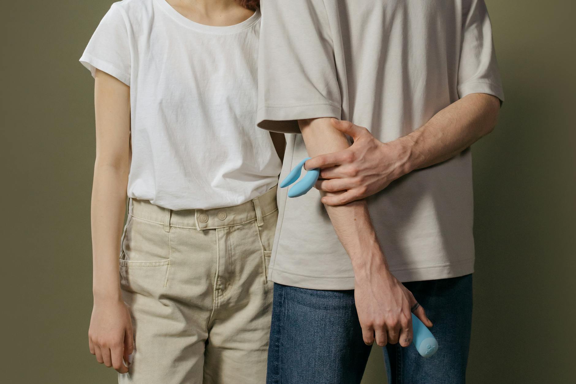 A blue clitoral vibrator held in hand against a purple background, symbolizing self-care and intimate healing.