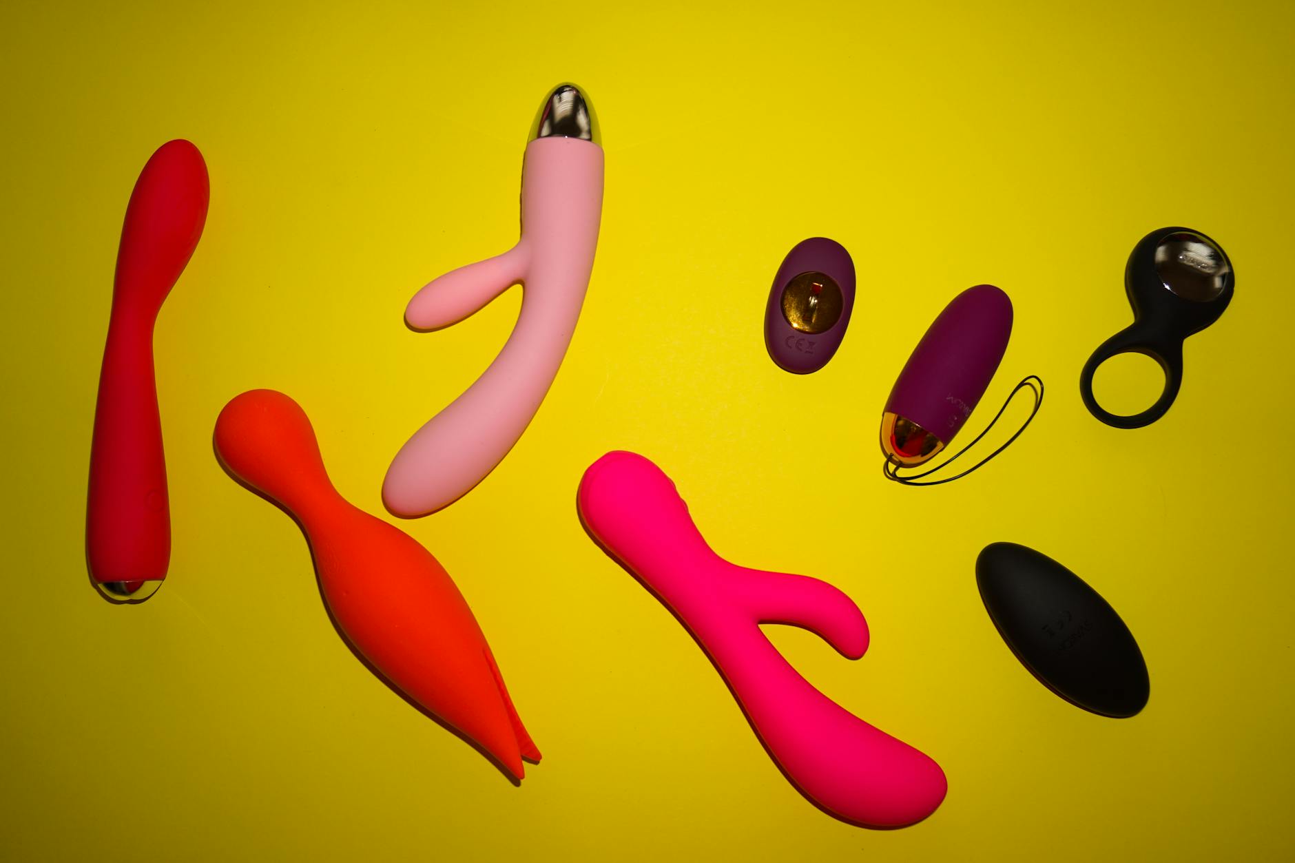 Vibradores coloridos e brinquedos sexuais de design variado em superfície amarela brilhante